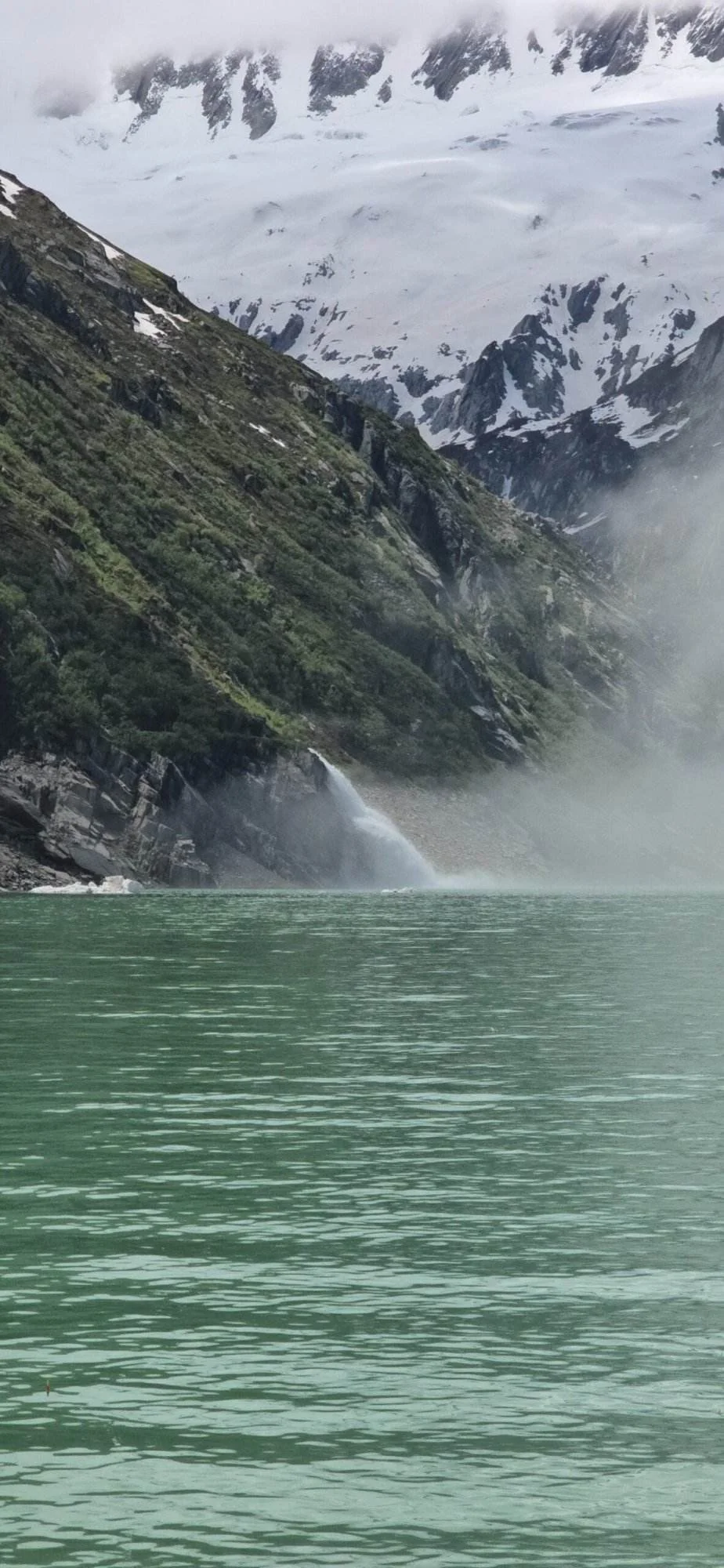 Göscheneralpsee: Türkisfarbener See vor schneebedeckten Bergen und Wasserfall.