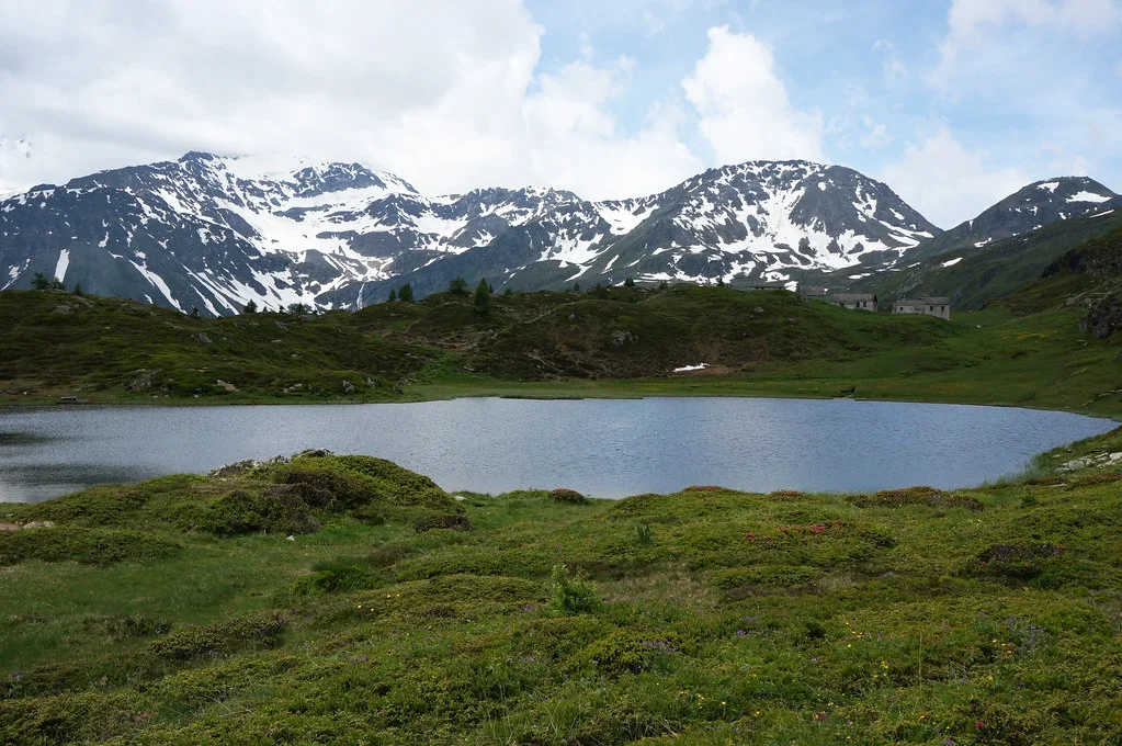 Hopschusee in den Schweizer Alpen mit schneebedeckten Bergen und grüner Landschaft.