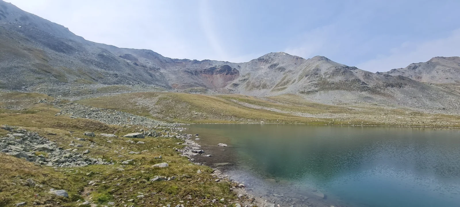 Illsee: Bergsee mit felsigem Ufer und Bergen im Hintergrund.