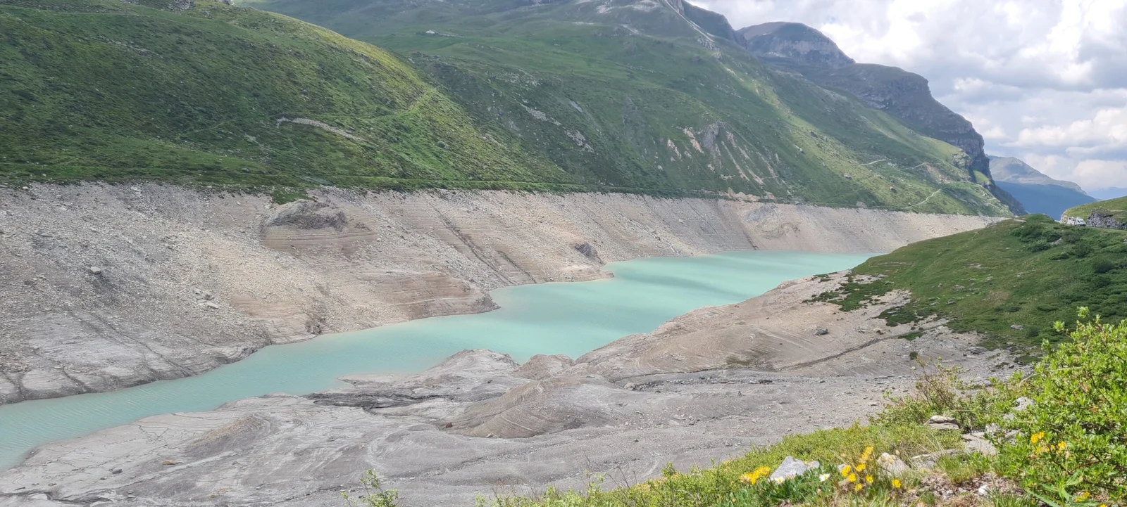 Türkisblauer Lac de Moiry in den Schweizer Alpen mit freiliegendem Ufer und grünen Hängen.