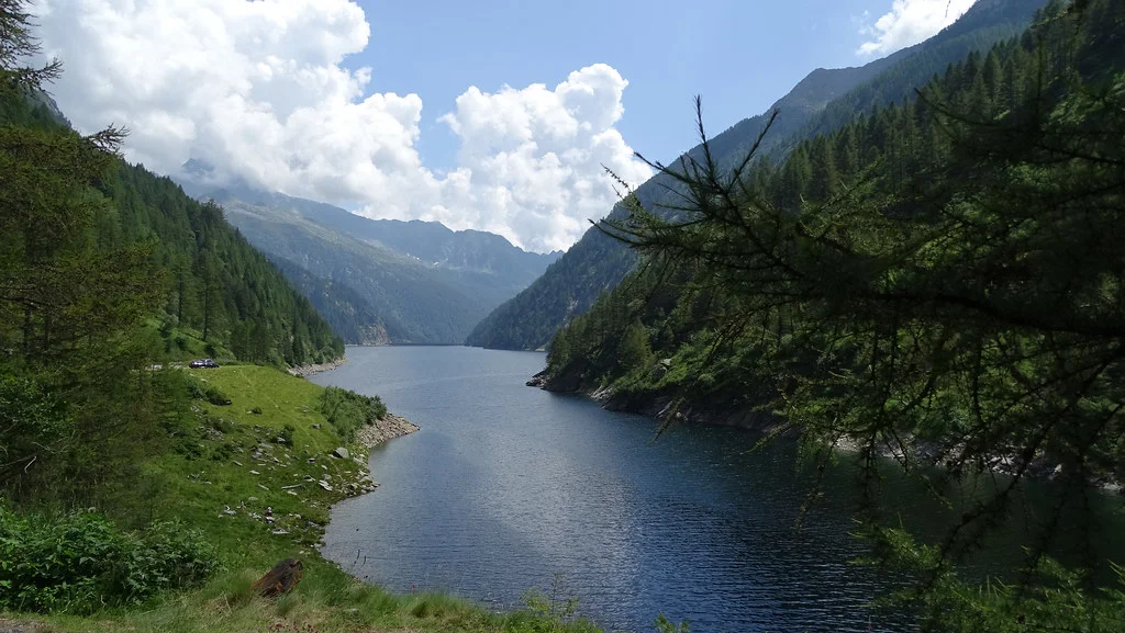 Lago del Sambuco mit Bergen und bewaldeten Ufern an einem sonnigen Tag.
