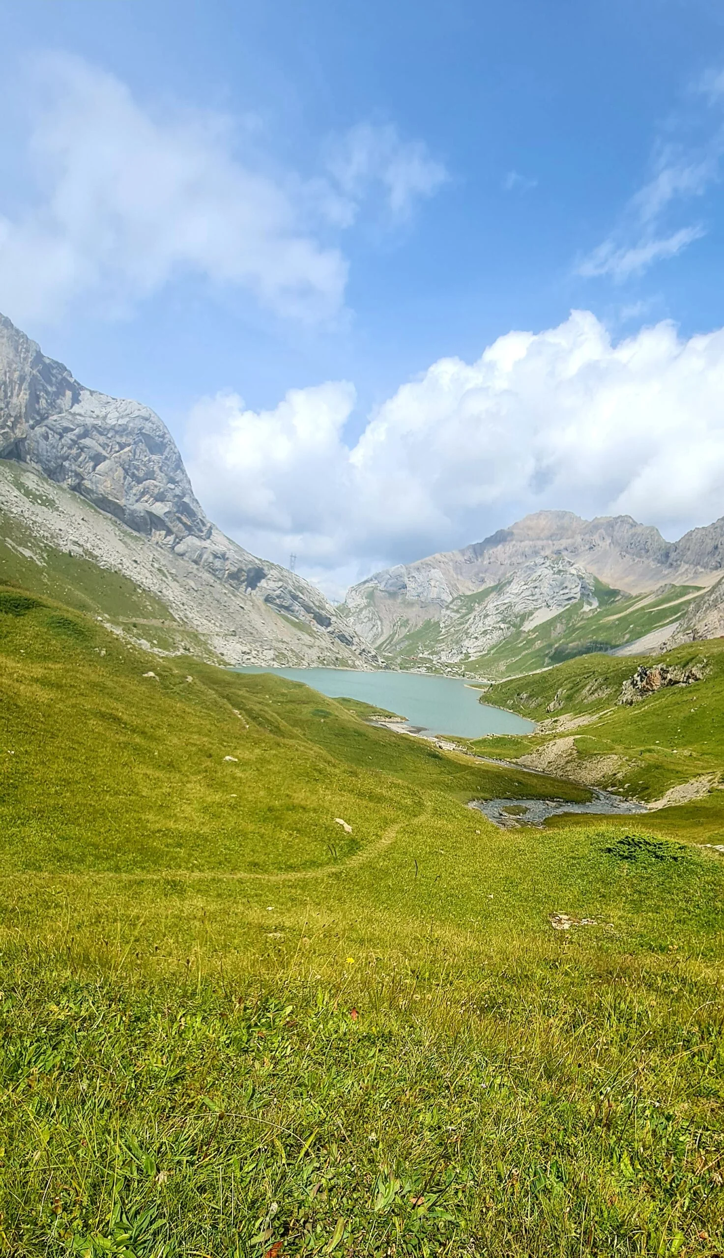 Idyllischer Lac de Sanetsch in einer grünen Berglandschaft unter blauem Himmel.