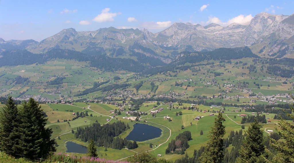 Schwendisee: malerische Berglandschaft mit Seen, grünen Wiesen und bewaldeten Hügeln.