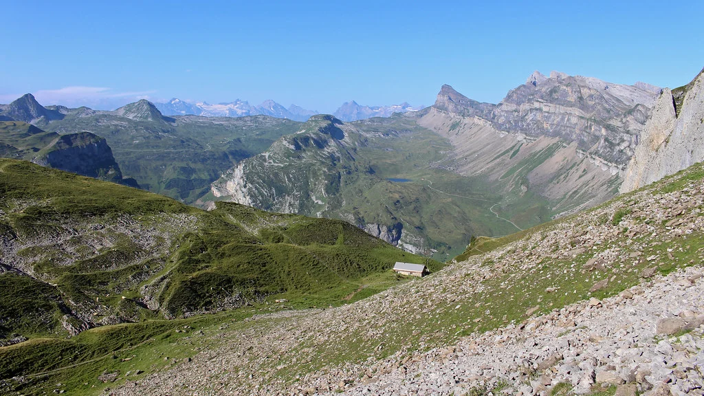 Seenalper Seeli: Berglandschaft mit Hütte und blauem Himmel. Grüne Hänge und felsige Gipfel.
