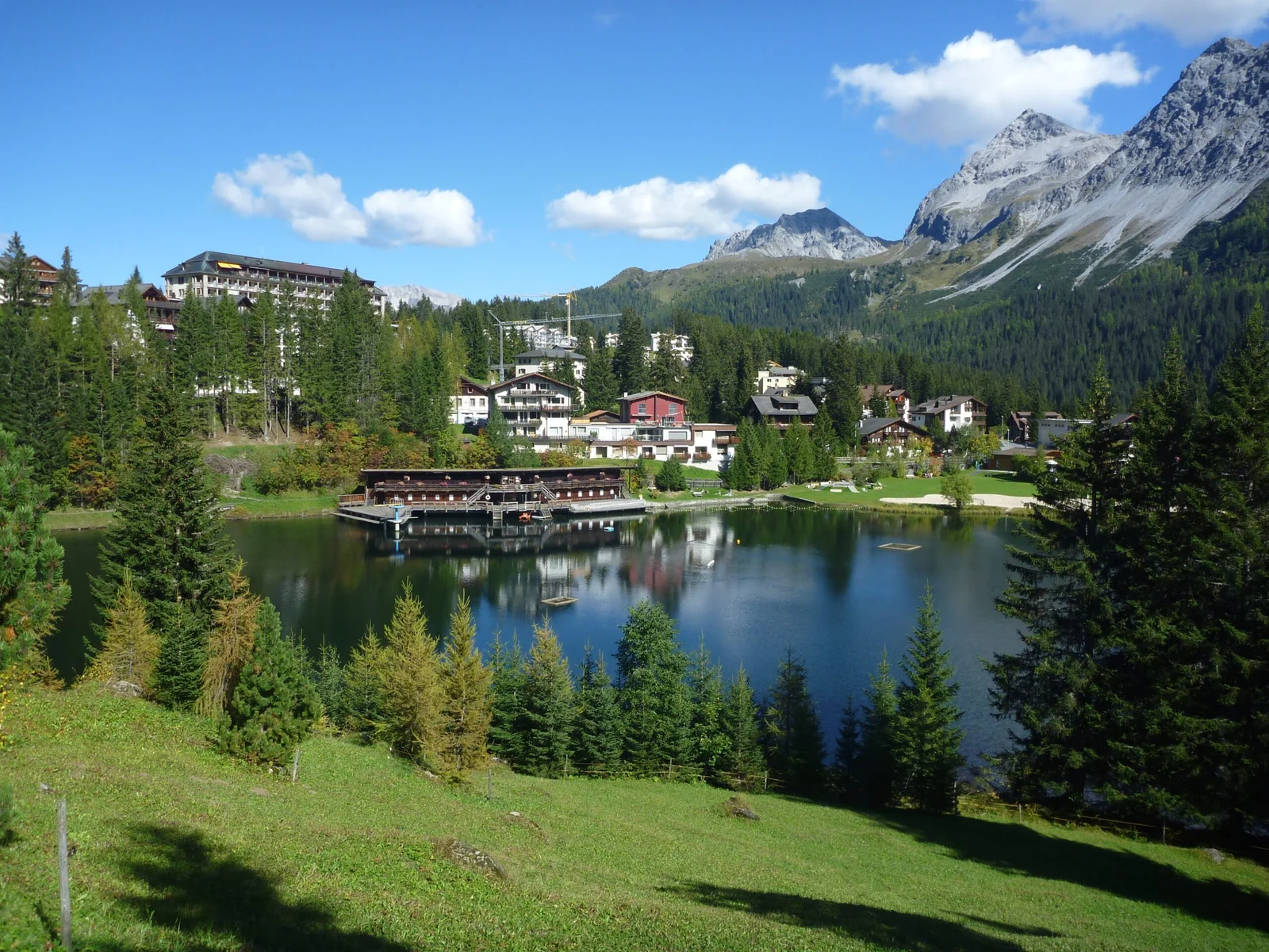 Untersee Arosa mit Bergpanorama, Häusern und Bäumen. Spiegelung im See.