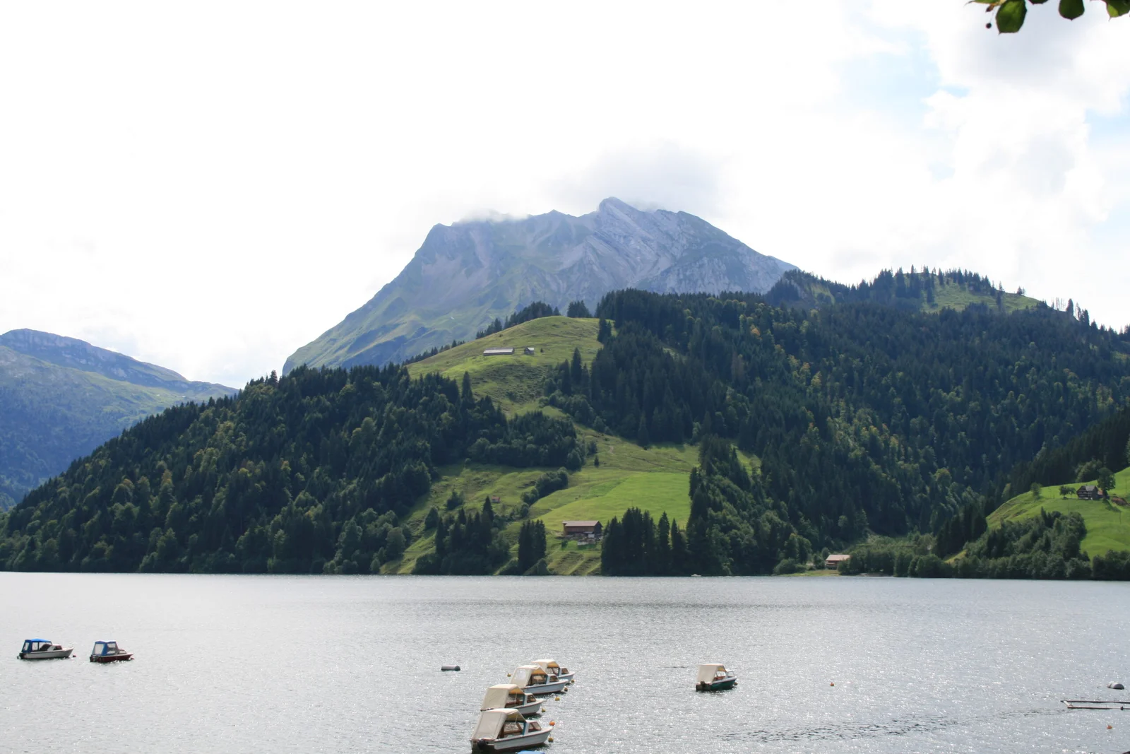 Wägitalersee mit Bergen, bewaldeten Hängen und Booten auf dem Wasser.